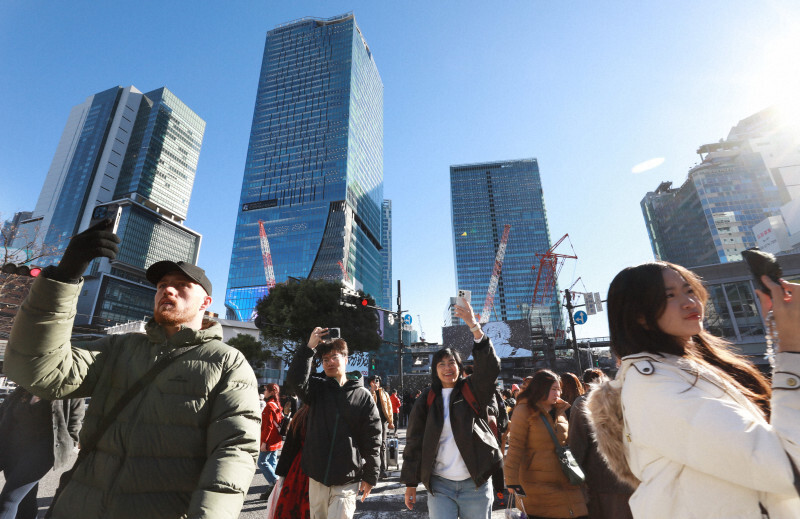 高層ビルが建ち並ぶ渋谷駅前でスマートフォンを掲げながら歩く人たち＝東京都渋谷区で2024年12月23日、小出洋平撮影