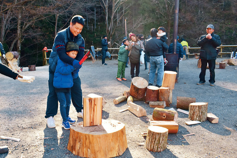 薪割りを手伝うツアー参加者＝15日午前、横瀬町のあしがくぼの氷柱会場