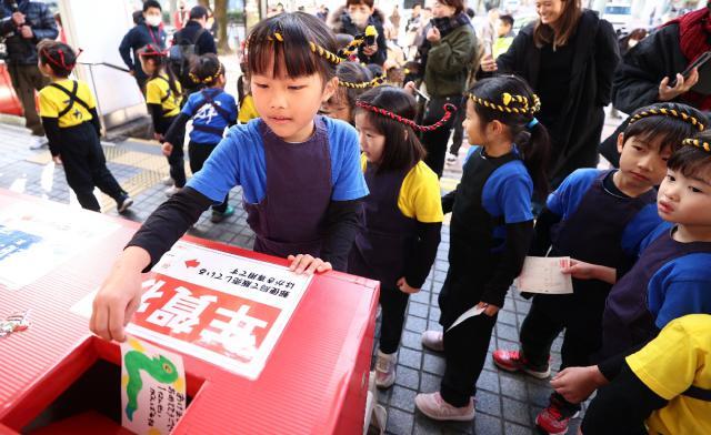 受け付け開始に合わせ、年賀状を投函する園児たち＝１６日午前、宮崎市・宮崎中央郵便局