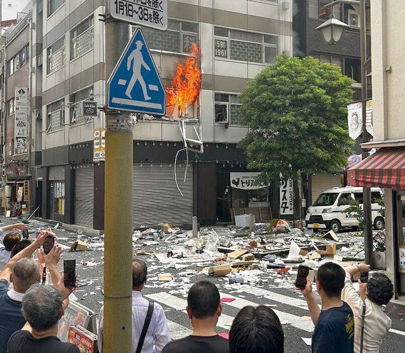 炎が上がる新橋ビル爆発火災の現場。道路には段ボールなどが散乱していた＝7月3日午後3時ごろ、東京都港区（読者提供）