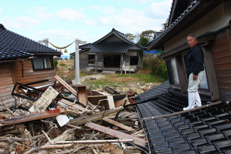 生まれた時から過ごした自宅の屋根で、土砂で流された家具などを見つめる南仁さん＝石川県珠洲市仁江町で2024年11月25日、稲生陽撮影