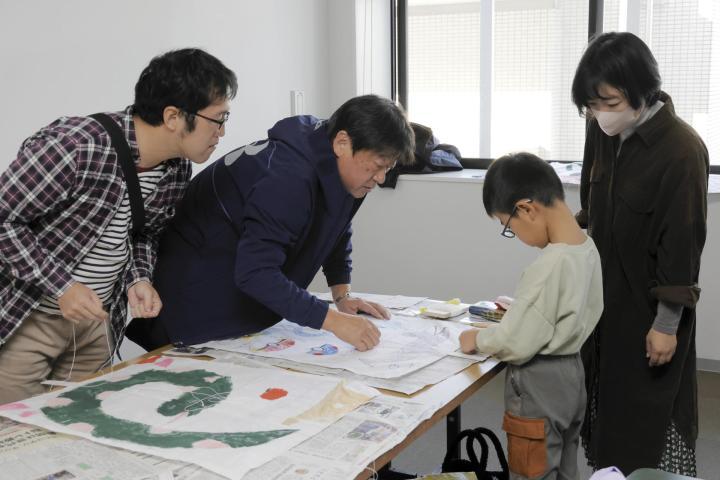 東予凧の会の会員と一緒に和だこを作る親子連れ