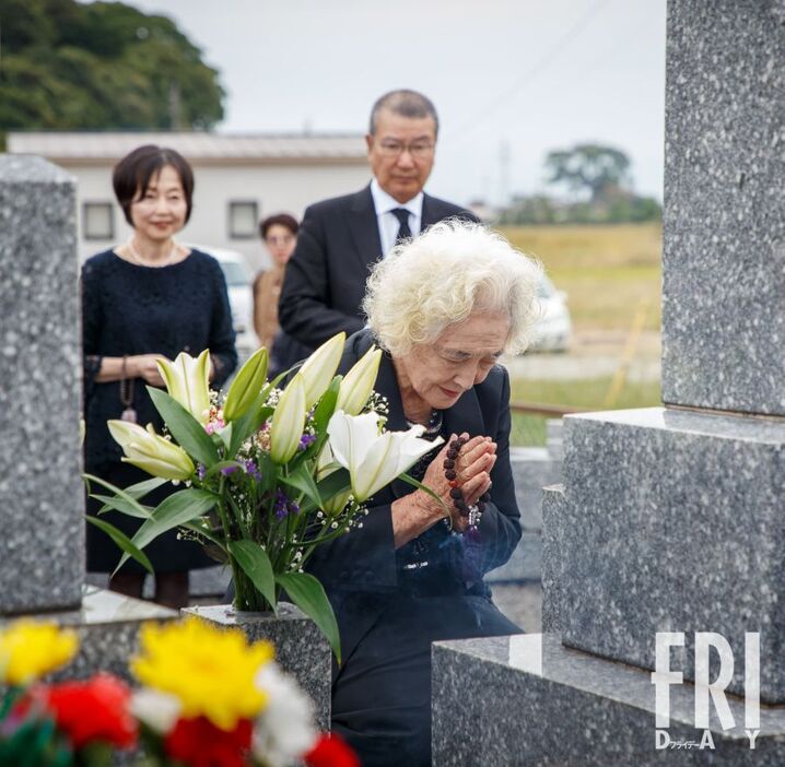 墓前で手を合わせる、高倉健の妹・森敏子。後ろの男性は東宝の島谷能成会長で、密葬の際の参列者でもある