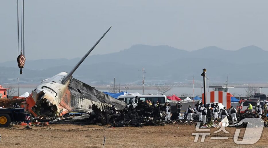 30日午前、全羅南道の務安国際空港で残骸を捜索する消防隊員＝共同取材(c)news1