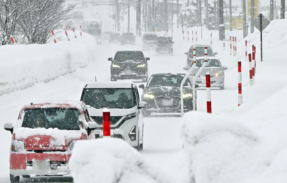 青森市内の道路では降りしきる雪の中、スローペースで車列が進んだ＝29日午後1時10分、青森市西大野5丁目