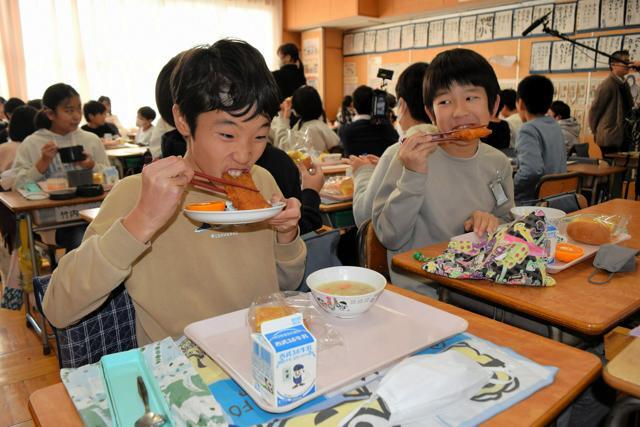 ファミチキにかぶりつく児童たち=2024年12月20日午後0時54分、埼玉県狭山市立入間川小学校、深津慶造撮影