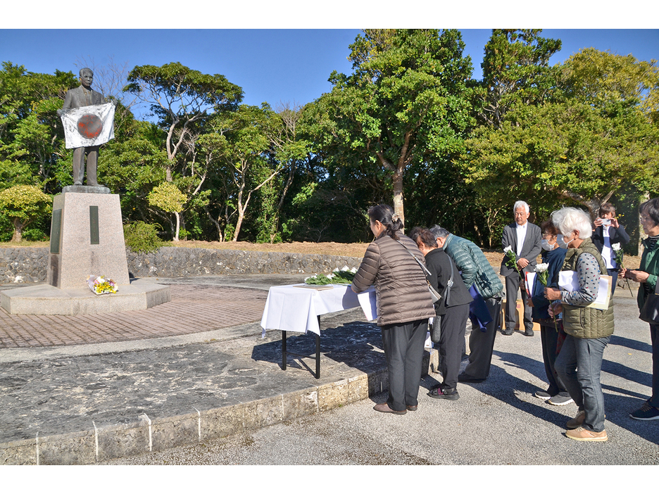 義名山公園にある泉芳朗頌徳記念像に献花をする参加者＝25日、鹿児島県伊仙町伊仙