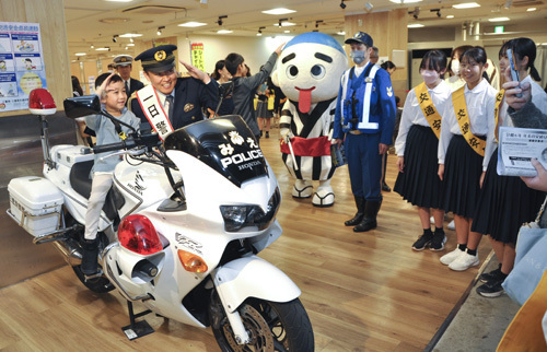 【白バイに試乗する子どもと一日警察署長の山田さん＝四日市市諏訪栄町の近鉄百貨店四日市店五階催事場で】