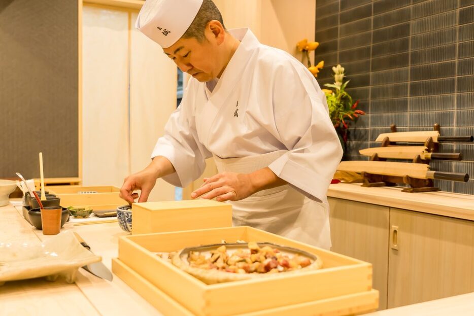 酢飯を入れたどんぶりに煮たしいたけなどの味のついた具と生の魚を重ねる