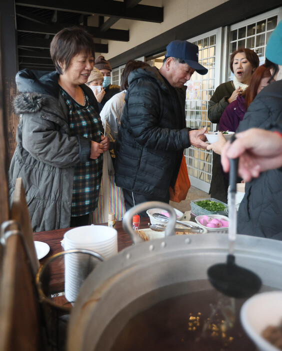 珠洲市役所前の「飯田わくわく広場」で、ボランティアによる年越しそばの炊き出しに並ぶ人たち＝３１日午後、石川県