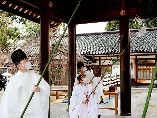 忌竹で外拝殿をきれいにする神職とみこ＝射水神社