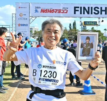 妻の弘美さんの遺影を持って完走した安藤誠さん＝１２月１日、那覇市・奥武山陸上競技場