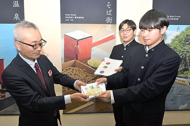 制作したキャラクターのキーホルダーとパンフレットを渡す（右から）天野夢希さんと斎藤大河さん＝村山市・観光物産館