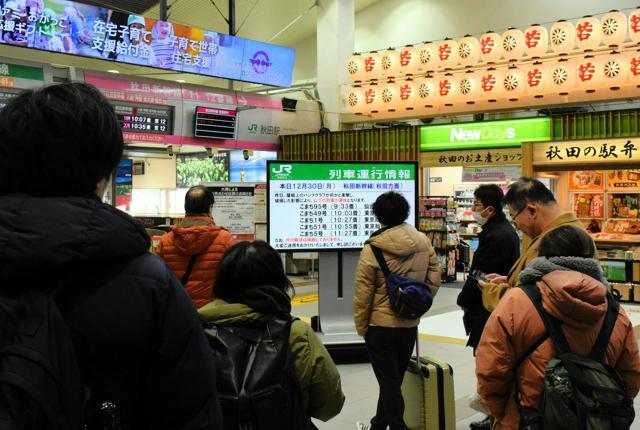 東京行きの新幹線「こまち」の運休を知らせるボードを見つめる人たち==2024年12月30日午前8時0分、秋田市、滝沢隆史撮影