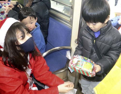 【プレゼントの菓子を手にする男児＝東員町の三岐鉄道北勢線東員駅で】