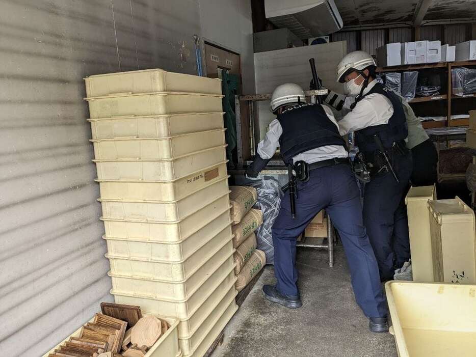 クマが入った倉庫の入り口を押さえる警察官ら＝4月18日、京都府福知山（同市提供）