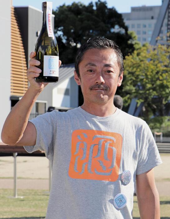 ダム構造物のトンネルで貯蔵、熟成させた日本酒を手にするプロジェクト実行委員長の渡会充晃さん＝2024年10月、名古屋市