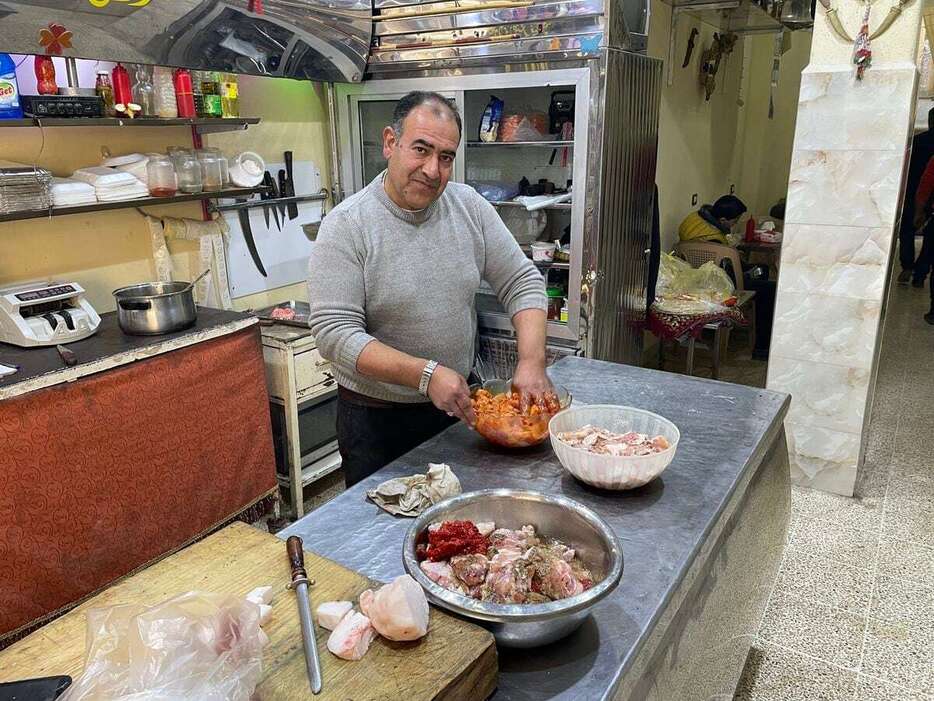 16日、シリアの首都ダマスカス近郊のドゥマにあるラクダ料理店で、ラクダ肉に下味をつける店主。「ラクダ肉を食べると元気が出るぞ」と笑った（大内清撮影）