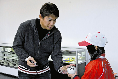 子どもにサインボールを渡す角中選手（左）（２９日、七尾市で）