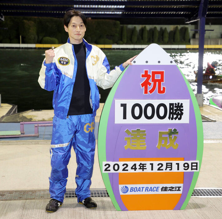 通算１０００勝の記録ボードを持って記念撮影する河合佑樹