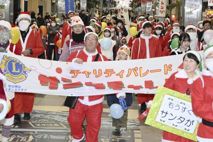 クリスマスソングを歌いながら陽気に行進する参加者＝22日午前、松山市大街道2丁目