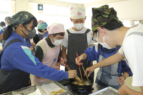 【ジャガイモを付けたカマスを揚げる生徒ら＝紀北町相賀の町立潮南中学校で】