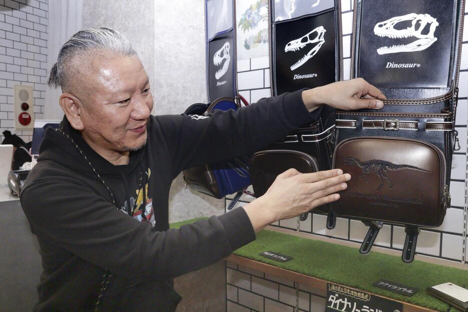 恐竜ランドセルにあしらわれた刺しゅうを説明する山田耕一郎さん＝10月、福井県越前市