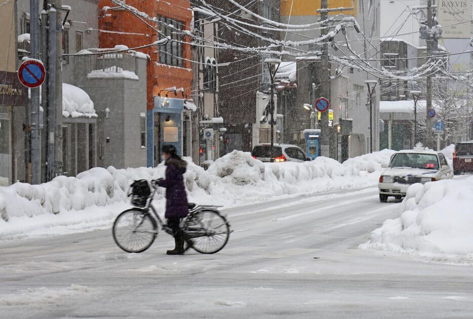 雪が降る青森市で自転車を押す人＝22日午後