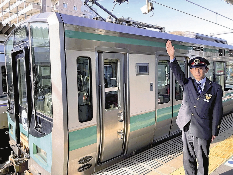 制服姿で電車に出発合図を送る一日駅長のイメージ写真＝JR西日本提供