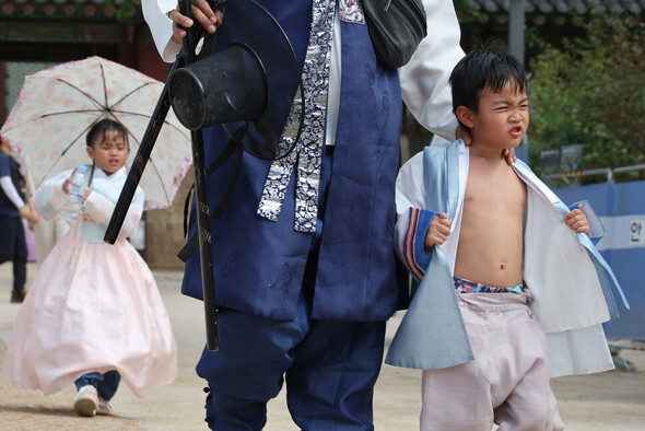 秋夕連休の最終日である9月18日午後、ソウル鍾路区の景福宮で、韓服を着た子どもが上着をはだけて暑さをしのいでいる。気象庁は同日午前、江原道と京畿道北部を除いた全国ほとんどの地域に猛暑特報を発令した＝キム・ヘユン記者