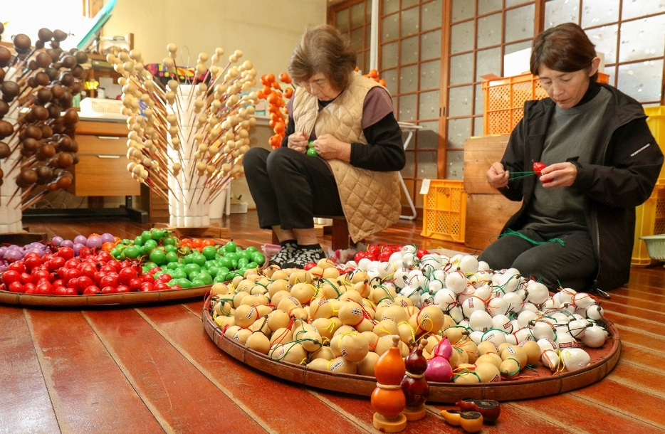 着色したひょうたんに飾りひもなどを結び付ける作業に精を出す繁専務（右）ら＝宇佐市南宇佐の溝口ひょうたん本舗