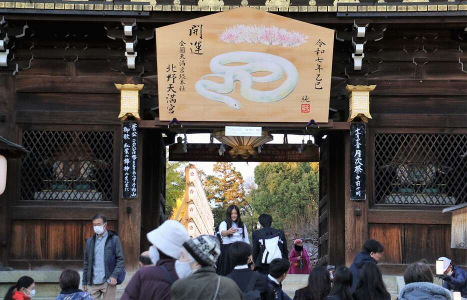 設置されたジャンボ絵馬の下を通り抜ける参拝者ら＝５日、京都市上京区