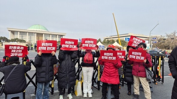 13日、ソウル永登浦区の国会議事堂向かいの大通りで行われた「尹錫悦大統領弾劾採決阻止」集会の参加者たちが、「違憲的弾劾反対」などの文言が記されたプラカードを掲げている=チョン・インソン記者