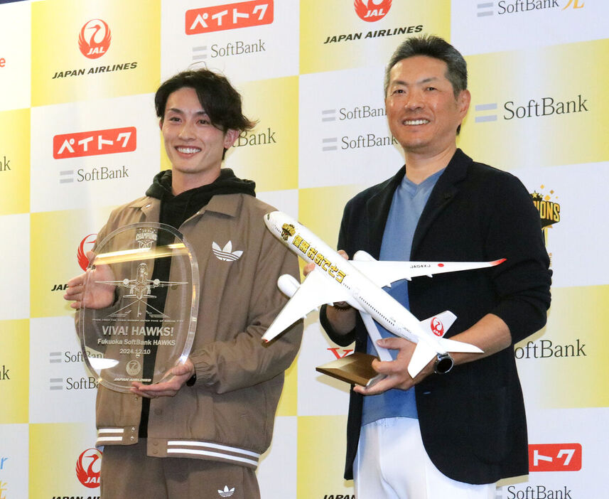 出発前、日本航空のスタッフから記念品を受け取った小久保監督（右）と周東（カメラ・田中　昌宏）