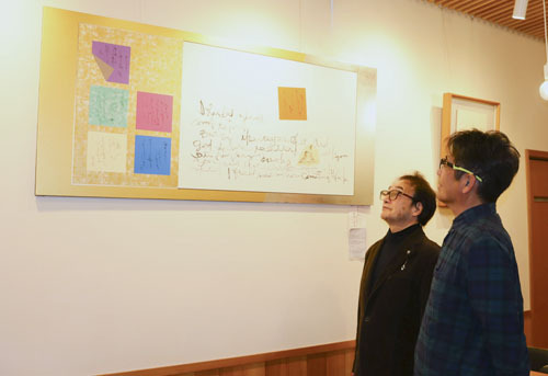 【「源氏物語　書作品展」の会場で作品を紹介する飯田さん（左）＝伊勢市宇治今在家町の茶房山中で】