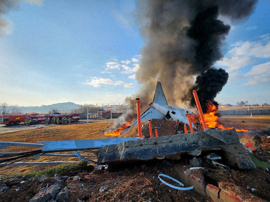 旅客機の炎上現場で消火作業に当たる消防隊員ら＝韓国南西部の務安国際空港で2024年12月29日、聯合・ロイター