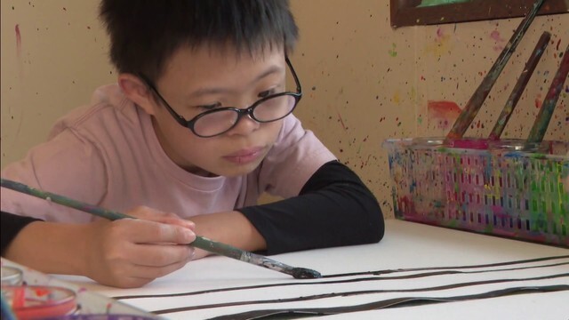 アトリエで絵を描くダウン症の少年