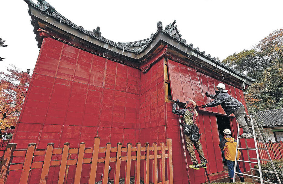 赤い杉板で建物を囲う作業員＝７日午前１１時１５分、金沢市丸の内の尾﨑神社