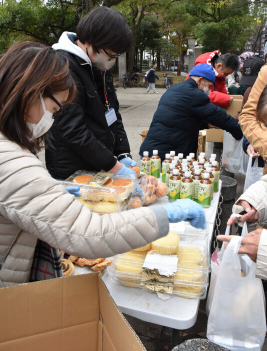 天神中央公園では支援者たち（左側）が生活困窮者ら（右側）にパンや飲み物を配っていた＝福岡市中央区で2024年12月29日午後2時18分、山口響撮影