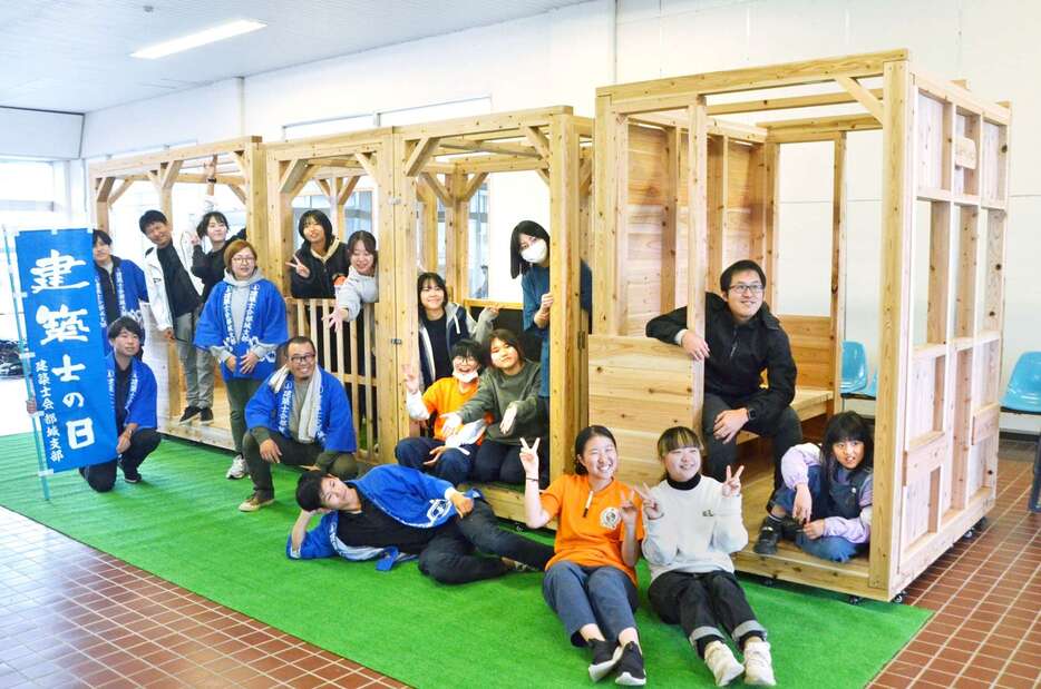 西都城駅１階コンコースに木製列車を完成させた都城高専の学生と県建築士会都城支部員ら＝都城市松元町