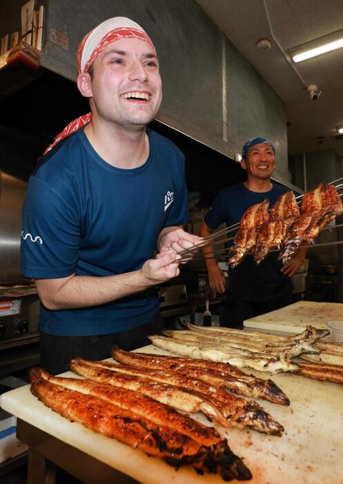 ウナギのかば焼き職人として働くアメリカ人のダニエル・ジンガニＪｒ．さん。右隣は師匠の西村大輔社長＝神戸市長田区久保町５、西村川魚店