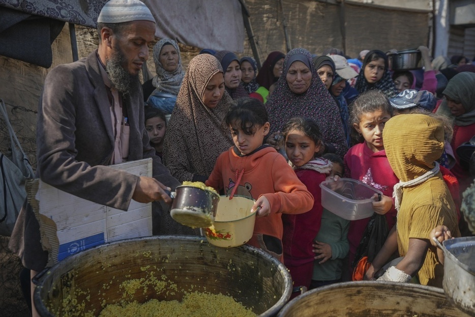 ガザ中部デールバラハで食料を受け取るパレスチナ人の子どもたち＝11月（AP＝共同）