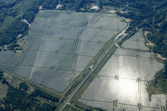 大規模な太陽光発電施設の周りに風車が立ち並ぶ=2024年10月13日、青森県六ケ所村、朝日新聞社機から、長島一浩撮影