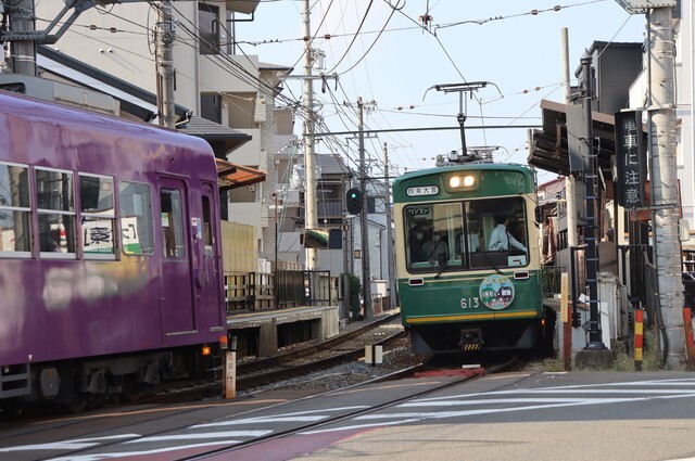 京紫色の嵐電車両と行き違うツートンカラーの電車（京都市右京区・蚕ノ社駅）