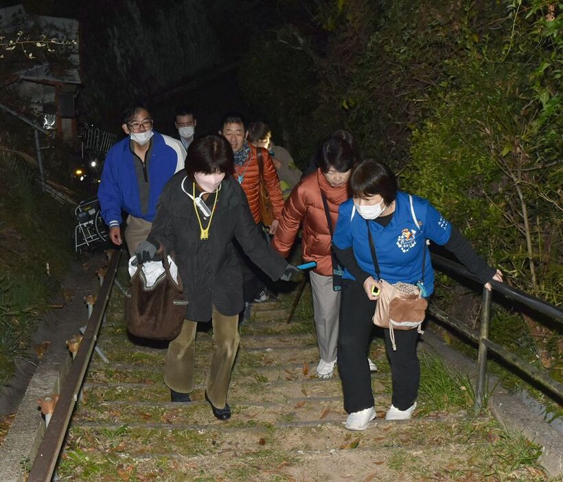 夜の避難訓練で、山への階段を上る市民活動センターの運営委員（１１日午後７時過ぎ、和歌山県田辺市高雄２丁目で）