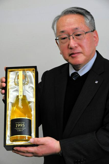 沢の鶴が発売する「1995年醸造　生酛（きもと）純米古酒」を持つ同社製造部部長の西向賞雄さん=2024年12月11日午後2時45分、神戸市中央区、西村宏治撮影