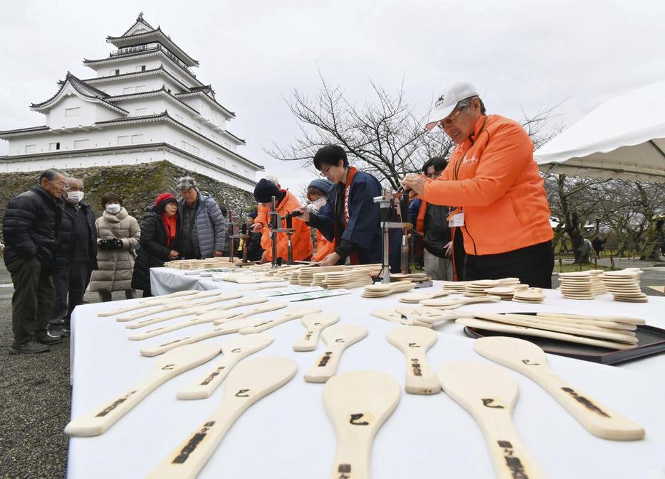 一枚ずつ丁寧に進められる「飯べら」の焼き印押し作業＝9日午前、会津若松市・鶴ケ城