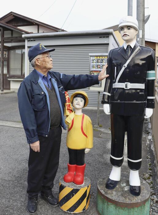 駐在所前に立つ人形に触れる地区交通安全協会の杉下吉身さん＝11月12日、岩手県住田町