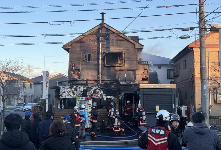 火災で焼けた飲食店舗兼住宅と消火作業を続ける消防署員ら=守谷市久保ケ丘