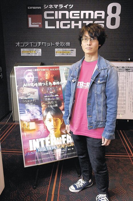 上映会場となる松本シネマライツで自作映画のポスターと並ぶ下向さん